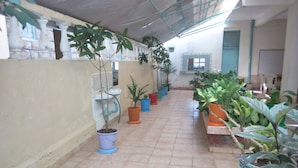 A corridor with tiled flooring, potted plants, a sink, and a window with a view of the outside.
