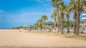 Una spiaggia con palme, una passerella di legno e un edificio con un cartello.