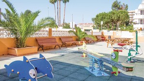 Un'area giochi per bambini con altalene, una struttura gioco a forma di elefante blu e panchine.
