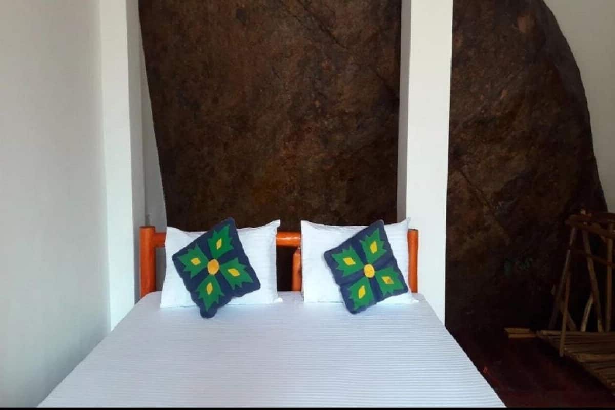 A bed with white bedding and two decorative pillows with a green and yellow pattern.