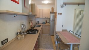 Una cocina compacta con encimera de madera, estufa a gas, fregadero y refrigerador.