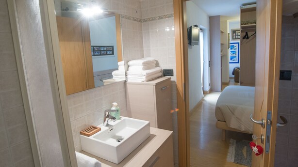 Un baño con lavamanos, espejo y toallas apiladas.