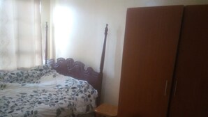 A bedroom with a bed, a wooden wardrobe, and a small wooden stool. - Juja Modern guest house (Juja)