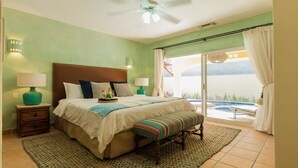 A bedroom with a bed, bedside tables, a bench, a view of a pool, and a ceiling fan. - CASA ESPERANZA in Pedregal, Cabo San Lucas (Pedregal)