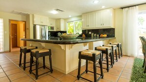 A kitchen with a large island, white cabinets, and a black countertop. There are six bar stools around the island. - CASA ESPERANZA in Pedregal, Cabo San Lucas (Pedregal)