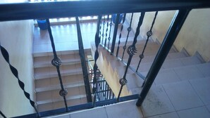 Eine Treppe mit schwarzen Metallgeländern und beigen Fliesen.