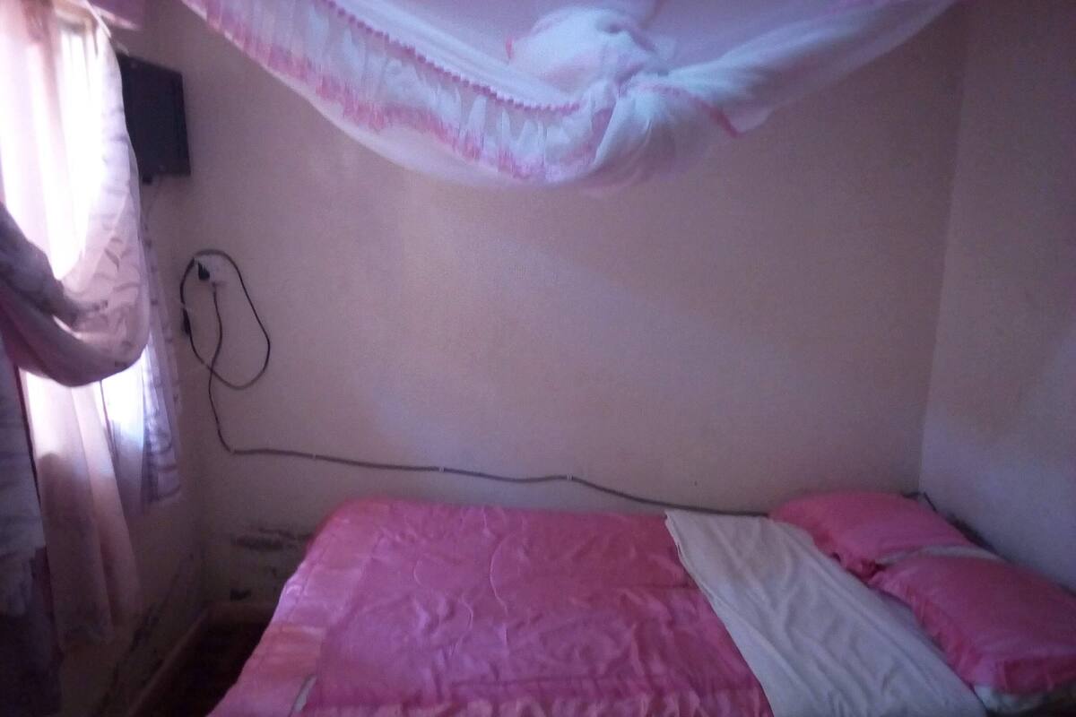 A bedroom with a bed, a power outlet, and a curtain.