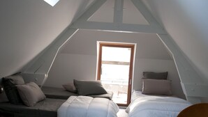 A small, cozy attic bedroom with two beds, a round table, and a chair. - Cottage overlooking Loire (Chênehutte-Trèves-Cunault)