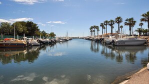 Una marina con barche ormeggiate lungo l'acqua, circondata da palme.