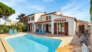Una casa a due piani con piscina, area relax all'aperto e giardino.