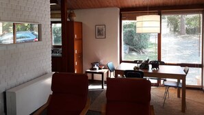 Une pièce chaleureuse avec un plafond en bois, une table à manger avec des chaises, un radiateur et une fenêtre avec des stores.