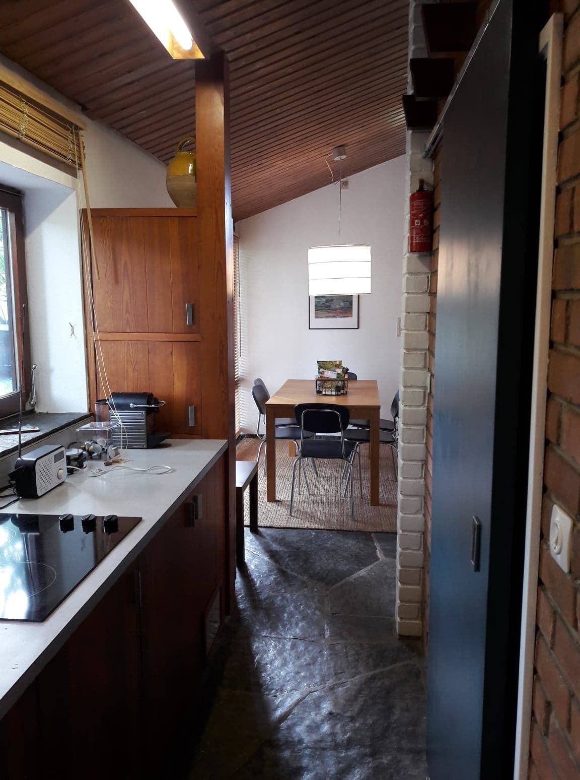 Una cuina amb un armari de fusta, una cuina i una zona de menjador amb taula i cadires.