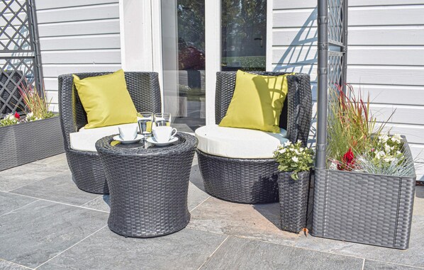 A patio with two wicker chairs and a small table, each with a cushion. There are potted plants and a glass door in the background. - 5 bedroom luxurious home in St-Martin-aux-Buneaux (St-Martin-aux-Buneaux)