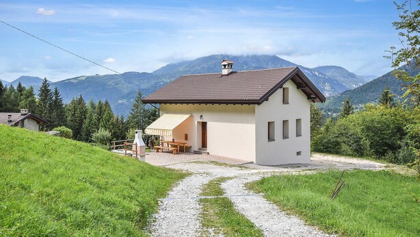 A small, single-story building with a sloped roof, a paved patio with outdoor furniture, and a gravel path leading to the entrance. - 3 bedroom beautiful home in Sovramonte (Sovramonte)