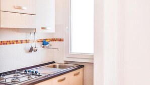 Una cocina con estufa a gas, un fregadero y un ventanal.