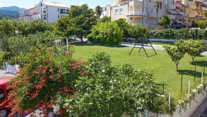 Una zona residencial con un parque arbolado, un columpio y edificios altos al fondo.