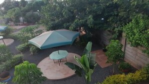 Un patio con una zona de estar circular, dos sombrillas y varias plantas.