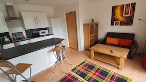 A compact living space with a kitchenette, a dining area, and a sofa. - Lovely, Light and Airy 1-bed Flat in Stornoway (Stornoway)