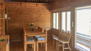 Un intérieur en bois comprenant une table à manger, des chaises et un vase rempli de fleurs.
