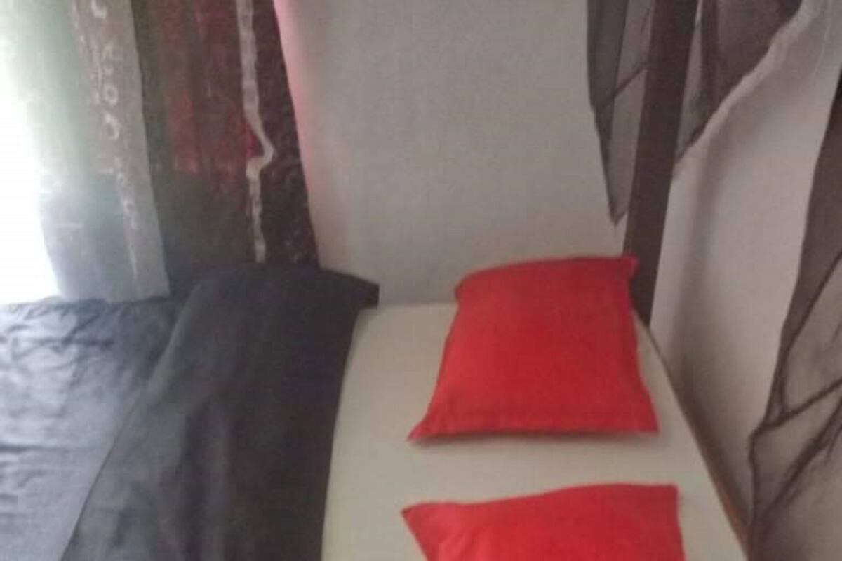 A bed with a black headboard and two red pillows.