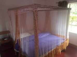 Uma cama de solteiro com dossel em um quarto com janela.