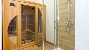 Un sauna avec une porte en bois, un espace de douche en verre et un panneau de commande sur la porte.