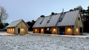 En toetages træbygning med skråt metal tag, der har en stor indgang og en mindre tilbygning.