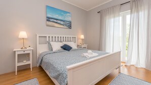 A bedroom with a bed, two bedside tables with lamps, a painting on the wall, and a window with curtains. - Stunning home in Benkovac (Benkovac)
