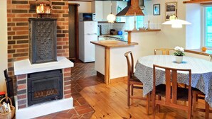 Een keuken met een bakstenen openhaard, een houten eettafel en stoelen.
