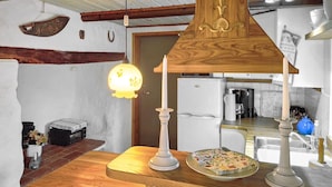 Een keuken met een houten aanrecht, een koelkast en een hangende lamp.