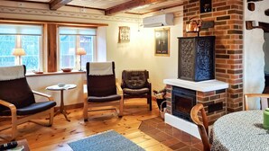 Een gezellige woonkamer met een open haard, houten vloeren en twee fauteuils.