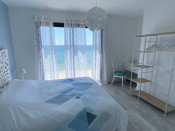 A bedroom with a bed, a chair, a desk, and a wardrobe.