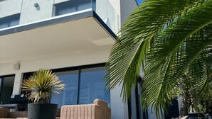 A modern house with a flat roof, large windows, and a small garden with a palm tree and a potted plant. - Villa Récampado - Feet in the water, pool and sea (Cavalaire-sur-Mer)