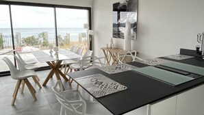 A modern kitchen with a large island, white bar stools, and a view of the ocean. - Villa Récampado - Feet in the water, pool and sea (Cavalaire-sur-Mer)