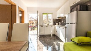 Eine moderne Küche mit weißen Schränken, einer schwarzen Arbeitsplatte und einem Edelstahl-Kühlschrank.