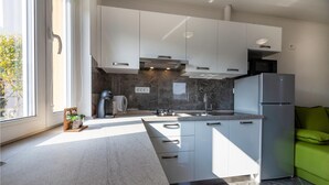 Eine moderne Küche mit weißen Schränken, einem Einbauofen, einer Spüle und einem Kühlschrank.
