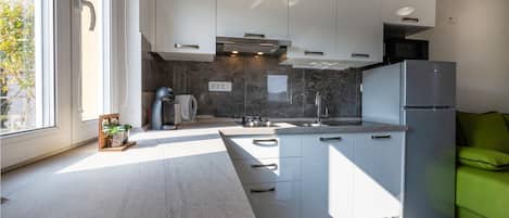 A modern kitchen with white cabinets, a built-in oven, a sink, and a refrigerator.