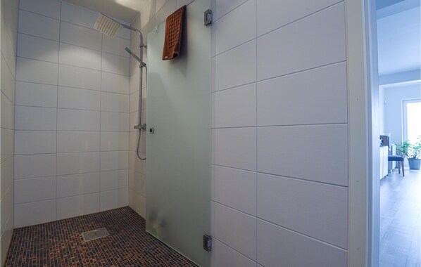 A modern bathroom with white tiles, a shower, and a patterned floor.