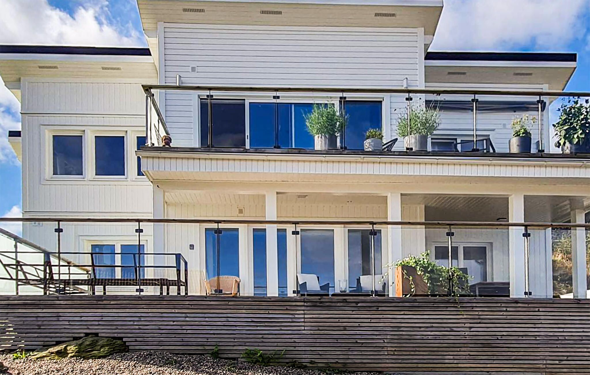 A two-story residential building with a balcony, outdoor seating, and potted plants.