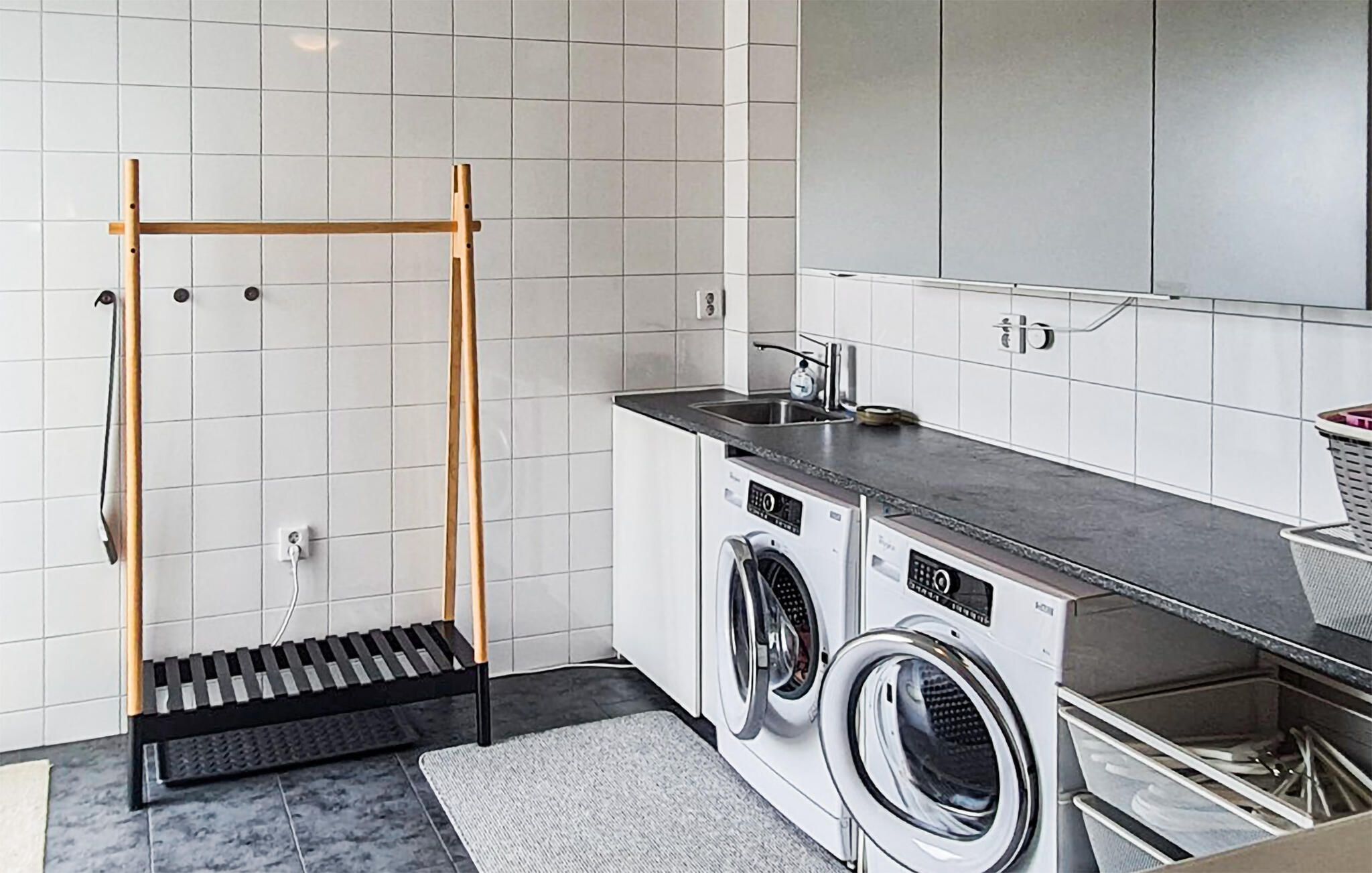 A laundry area with a washing machine, dryer, and a wooden drying rack.