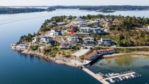 An aerial view of a coastal residential area with modern houses, a marina, and a lighthouse. - Cozy apartment in Svanesund with WiFi (Svanesund)