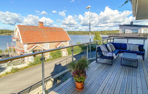 A balcony with a wooden deck, a blue sofa, and a potted plant.
