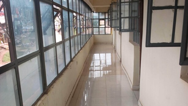 Un pasillo con ventanas amplias, suelo de baldosas y una lámpara en el techo.