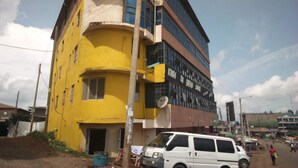 Un edificio de varios pisos con fachada amarilla y un letrero que dice 'Kings En Queens Lounge'.