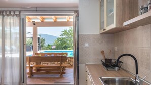 Cocina con encimera de madera, un fregadero y vistas a una piscina y zona de estar al aire libre.