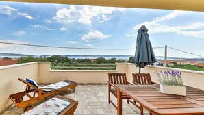 Eine Terrasse mit Holztisch und Stühlen, einer Bank und einem Blumentopf.