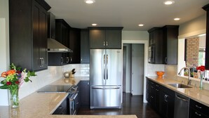 A modern kitchen with dark cabinetry, stainless steel appliances, and a marble countertop. - Gorgeous Riverfront Home, VHR# 073569, TOT# T65183 (Lotus)