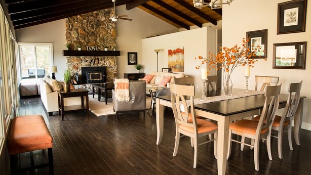 A spacious living area with a stone fireplace, a dining table with chairs, and a cozy seating area. - Gorgeous Riverfront Home, VHR# 073569, TOT# T65183 (Lotus)