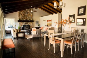 A spacious living area with a stone fireplace, a dining table with chairs, and a cozy seating area. - Gorgeous Riverfront Home, VHR# 073569, TOT# T65183 (Lotus)