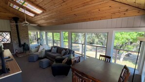 A spacious living area with a wooden ceiling, large windows, a fireplace, and a dining table. - Gorgeous Riverfront Home, VHR# 073569, TOT# T65183 (Lotus)